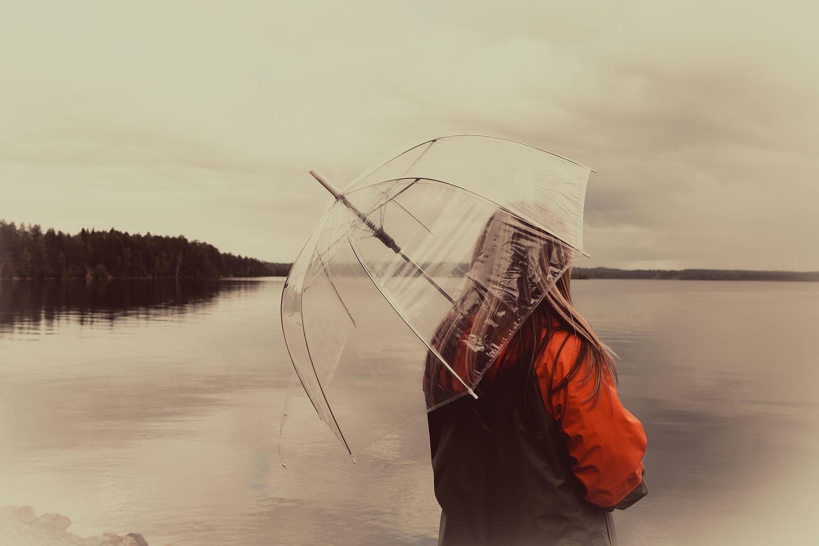 Nainen sateenvarjon alla syksyisessä ja sateisessa säässä