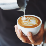 Henkilö kaataa cappucinoa