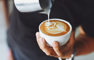 Henkilö kaataa cappucinoa