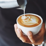 Henkilö kaataa cappucinoa