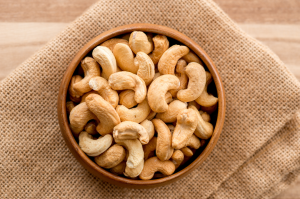 Kulhollinen cashew-pähkinöitä ruskealla kankaalla.