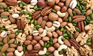 Lähikuva eri pähkinälajeista: cashew, manteli, pistaasi, saksanpähkinä, hasselpähkinä ja pekaanipähkinä värikkäässä sekoituksessa.