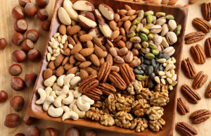 Lautasellinen erilaisia pähkinöitä: saksanpähkinöitä, manteleita, cashew-, pistaasi- ja brasilianpähkinöitä.