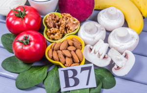 B7-vitamiinia eli biotiinia sisältäviä ruoka-aineita, kuten tomaatteja, sieniä, manteleita, saksanpähkinöitä, banaania ja punajuurta, aseteltuna värikkäästi pöydälle.