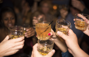 Ihmiset kilistävät laseja täynnä alkoholijuomia juhlatilanteessa.