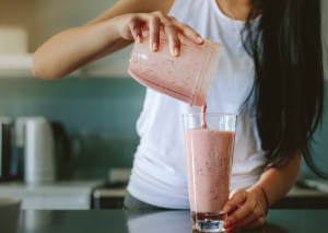 Kuvassa nainen kaataa smoothieta lasiin