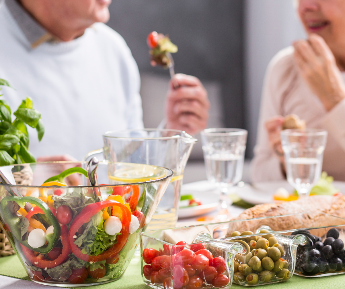 Kuvassa pariskunta syö yhteisen pöydän ääressä salaattia.
