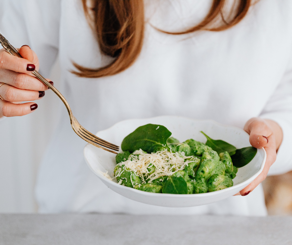 Kuvassa nainen syö pastaa, jonka seassa on pestoa ja pinaattia