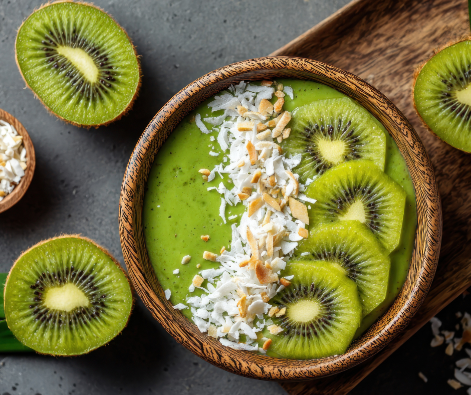 Kuvassa vihreä smoothiebowl, jonka päällä on kiiviviipaleita ja kookoshiutaleita.