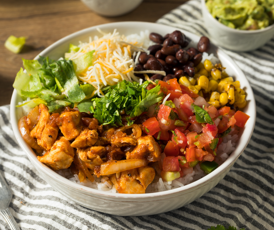 Kuvassa burritobowl, jossa papuja, maissia, tomaattia, juustoraastetta ja kanaa