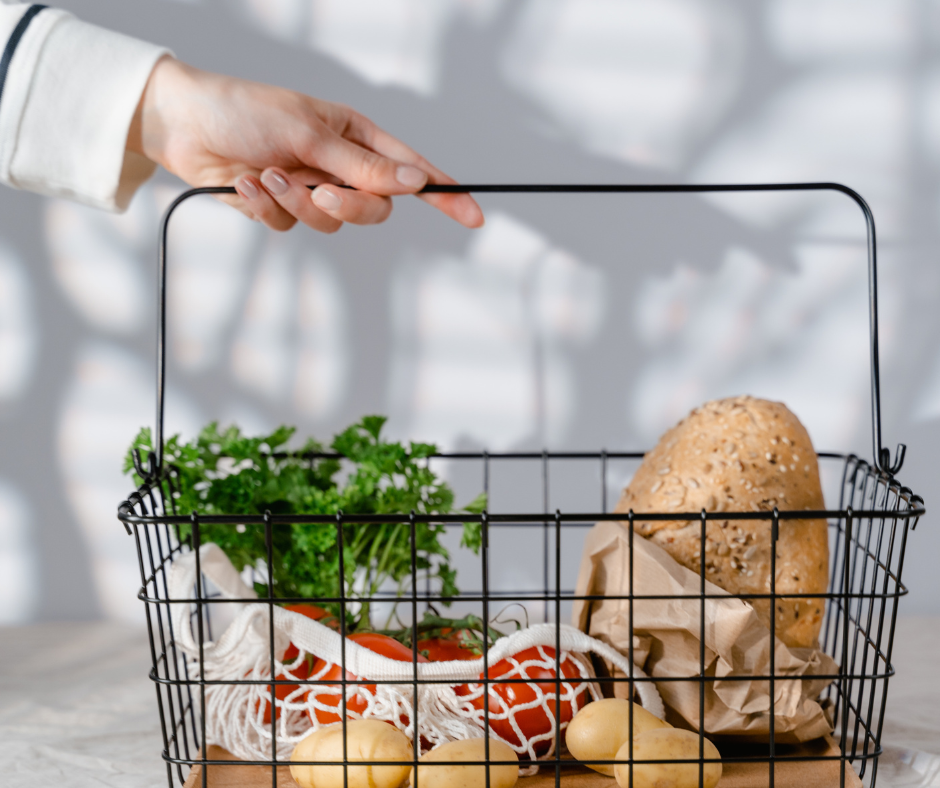 Ruokakauppaostokset mustassa korissa, löytyy leipää ja kasviksia