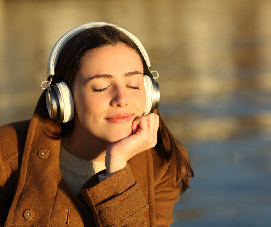 Kuvassa nainen kuuntelee musiikkia järven äärellä. Musiikin avulla voi palautua.