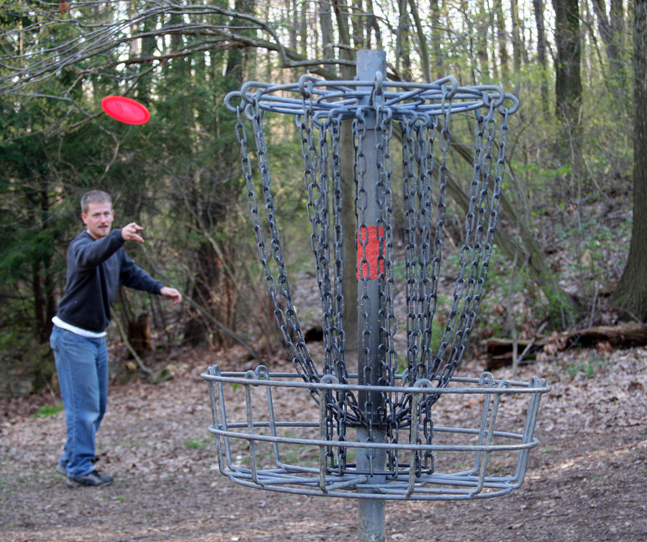 Kuvassa mies heittämässä frisbeegolf-kiekkoa metsässä.