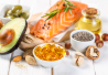 Kuvassa omega-3:n lähteitä kuten lohta, avokadoa, omega-3 kapseleita ja siemeniä.