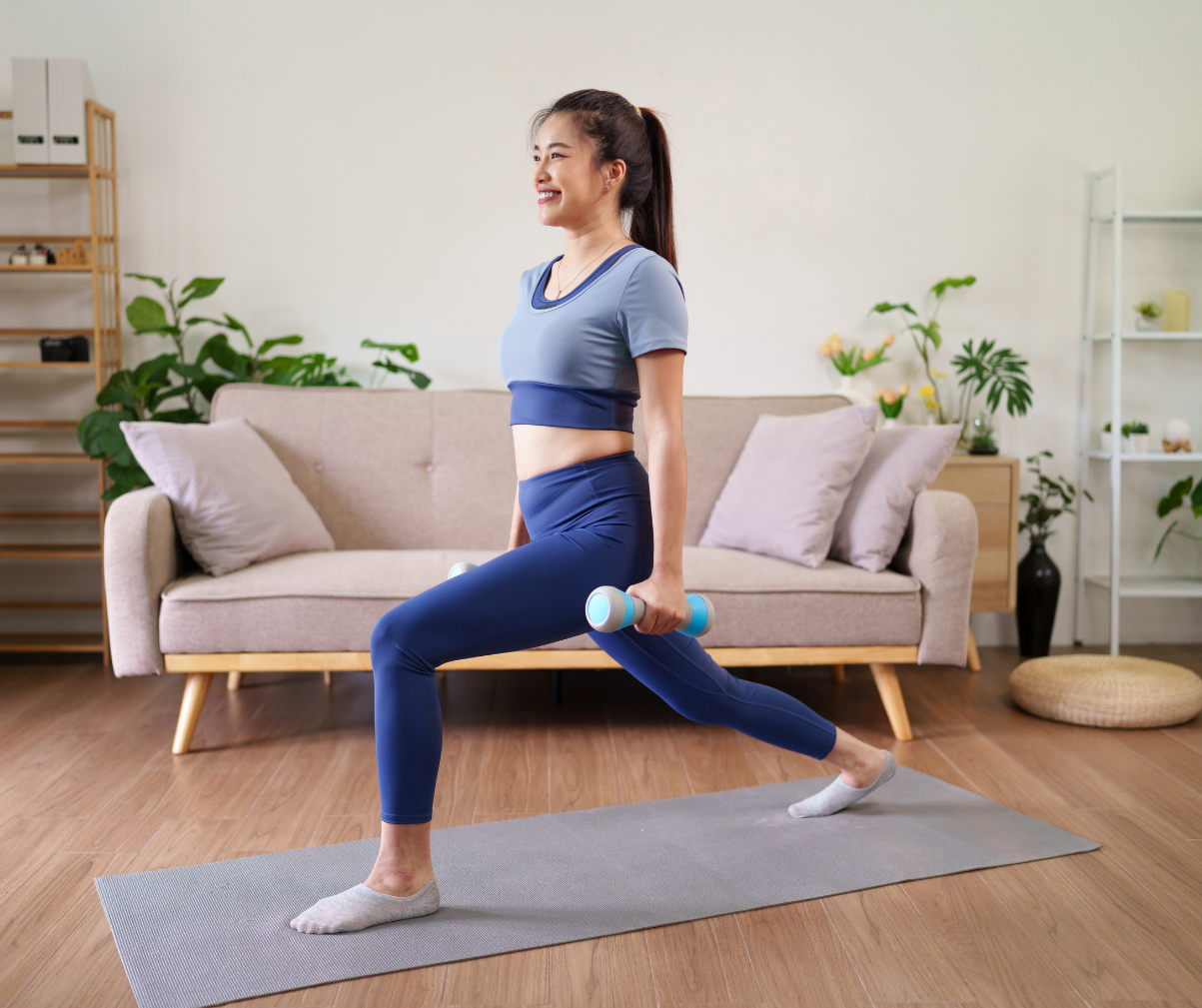Kuvassa nainen tekee askelkyykkyä kotona jumppamatolla.