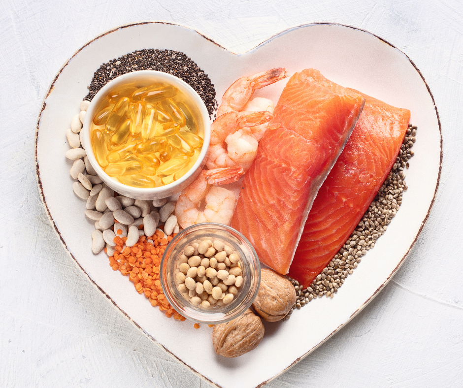 Kuvassa omega-3 happoa sisältäviä raaka-aineita sydämenmuotoisessa astiassa. On lohta, omega-3 kapseleita, rapuja, pellavansiemeniä, chia-siemenitä ja saksanpähkinöitä