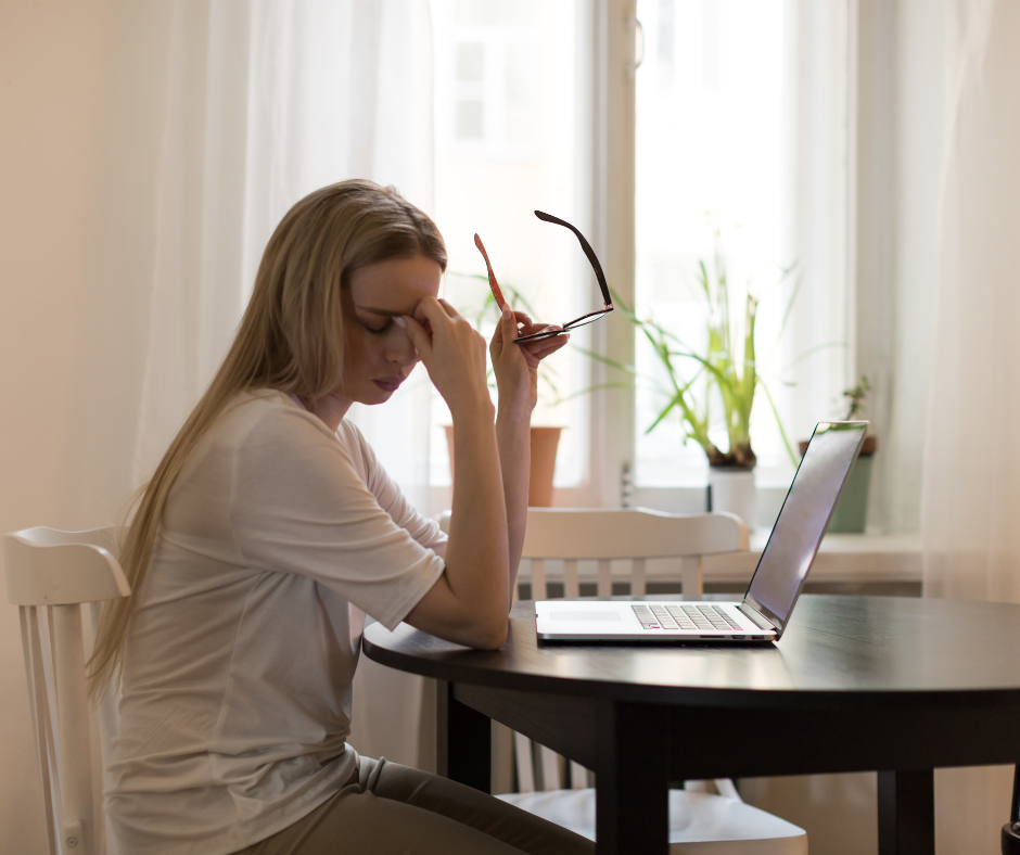 Kuvassa nainen on väsyneenä, pitelee otsaansa kädellä.