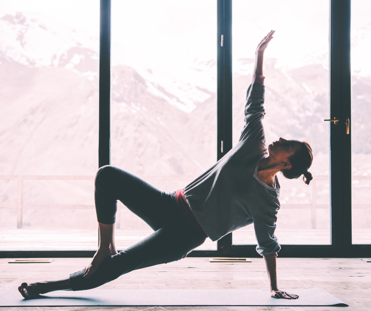 Kuvassa nainen venyttelee ikkunan edessä