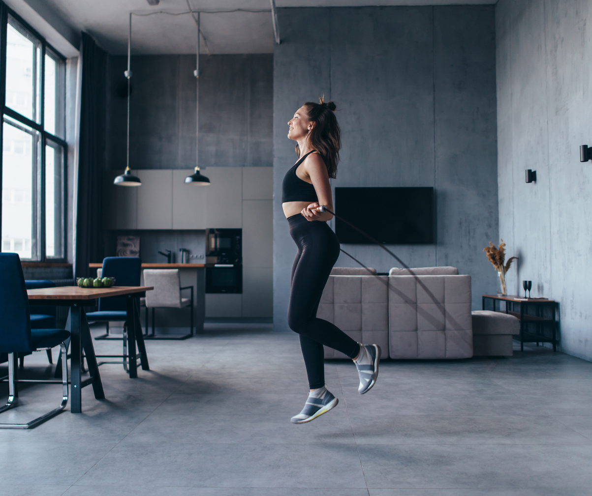 Kuvassa nainen hyppii hyppynarulla kotona