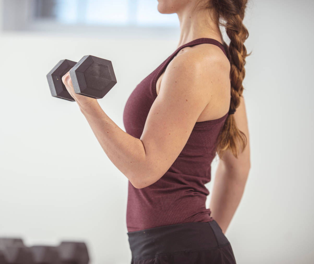 Kuvassa nainen tekee hauiskääntöä käsipainolla