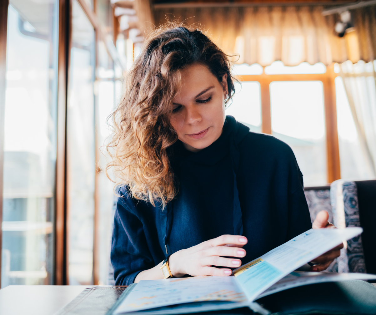 Kuvassa nainen ravintolassa tutkimassa ruokalistaa.