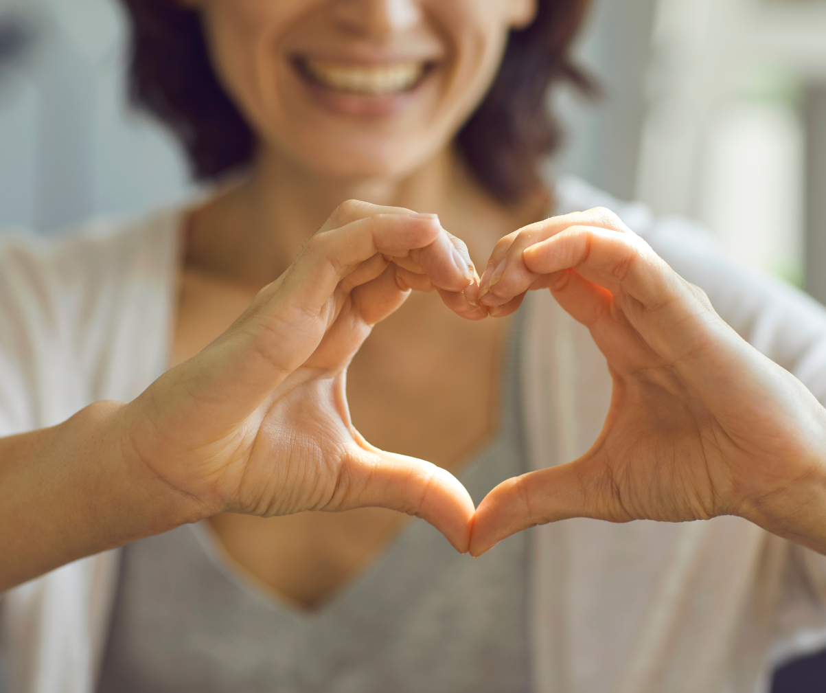 Kuvassa nainen näyttää sydäntä käsillään