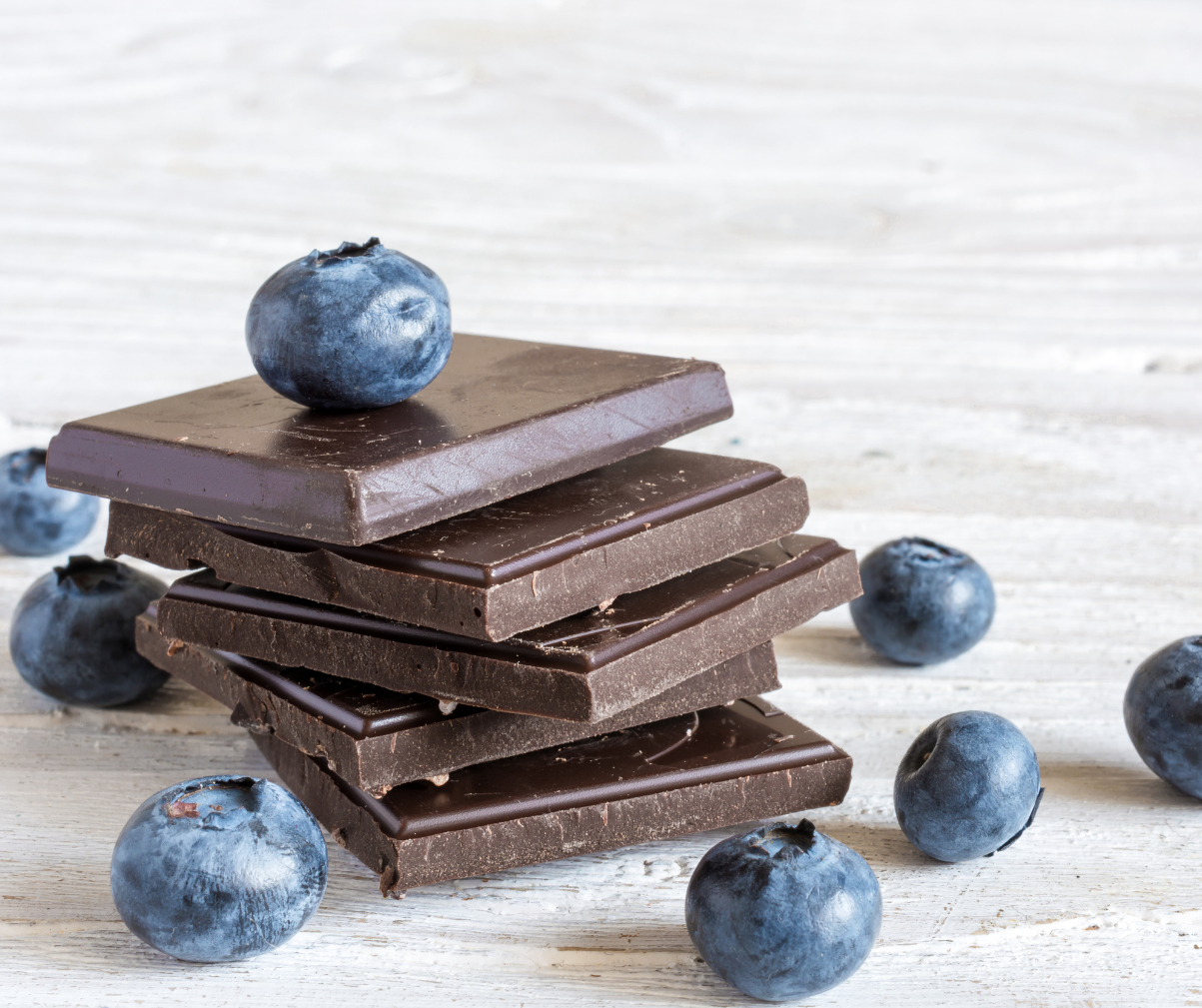 Kuvassa viisi palaa tummasuklaata ja mustikoita