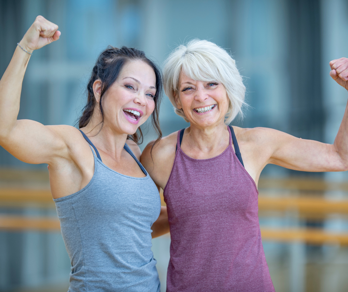 Kuvassa kaksi naista esittelee hauiksiaan iloisesti.