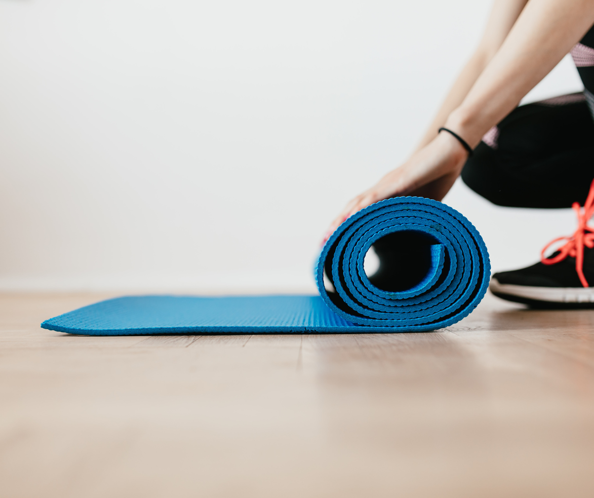 Kuvassa henkilö asettaa jumppamattoa lattialle
