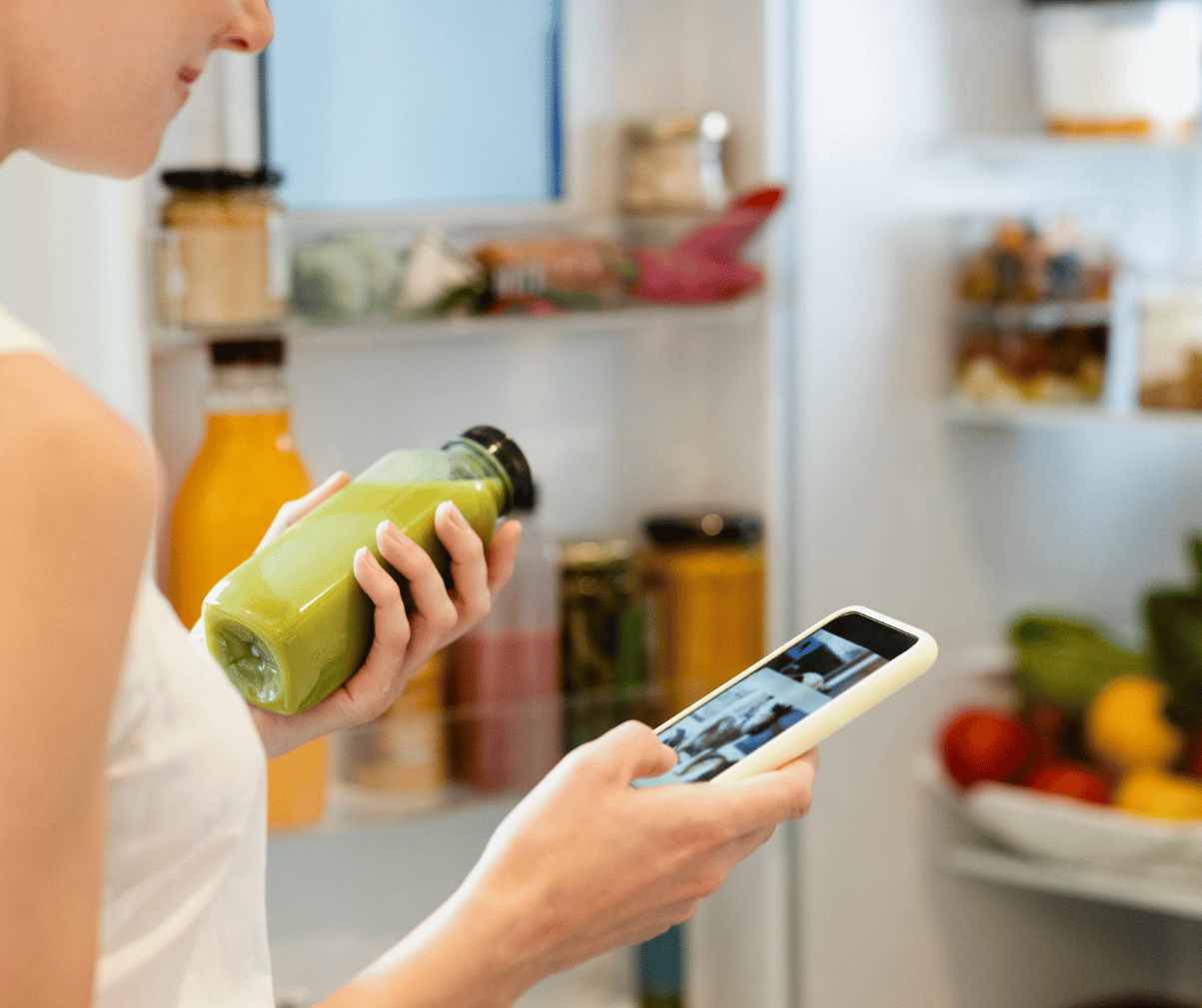 Kuvassa nainen ottaa jääkaapista smoothien ja merkitsee sen kalorisovellukseensa