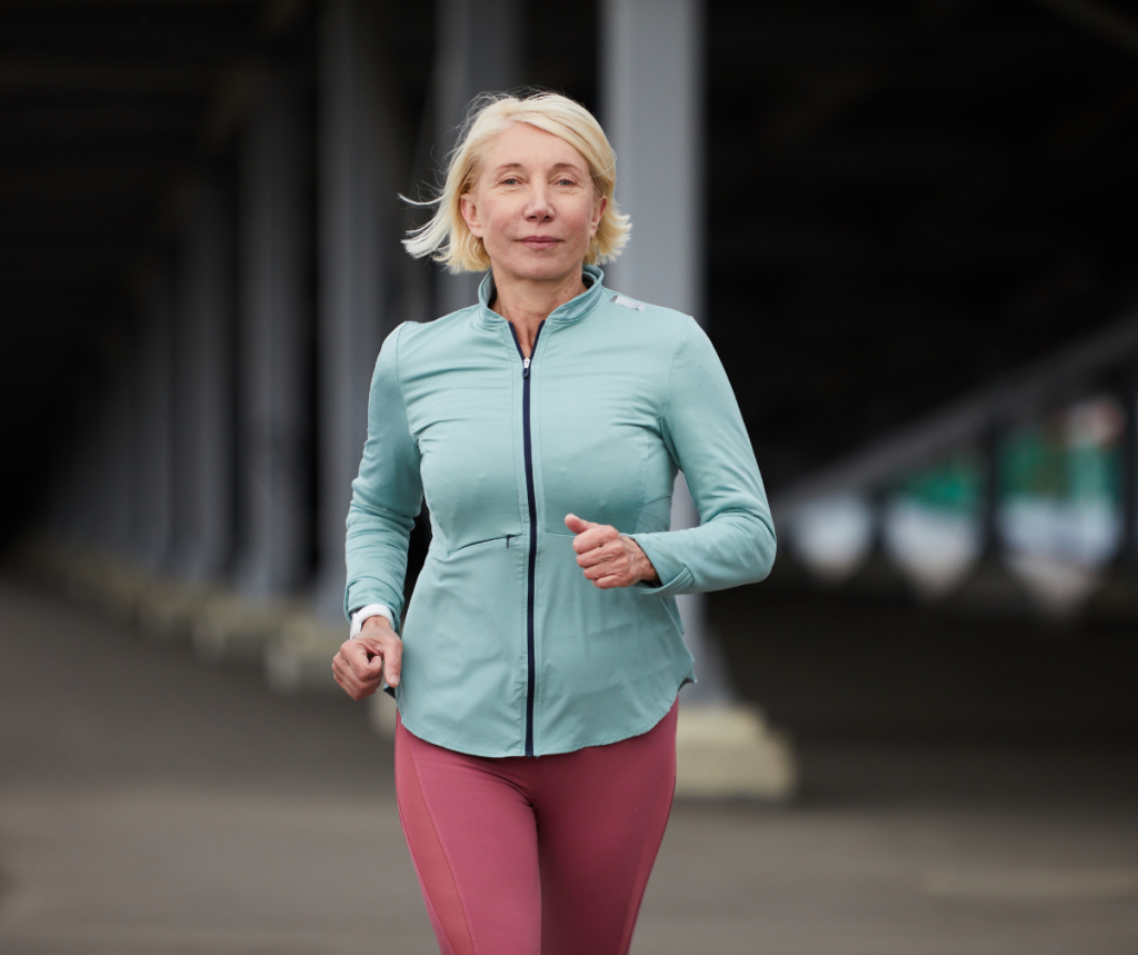 Kuvassa nainen tekee kävelytreeniä ulkona tuulipuvussa