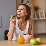 Kuvassa nainen syö jogurttiannosta, jossa on granaattiomenansiemeniä