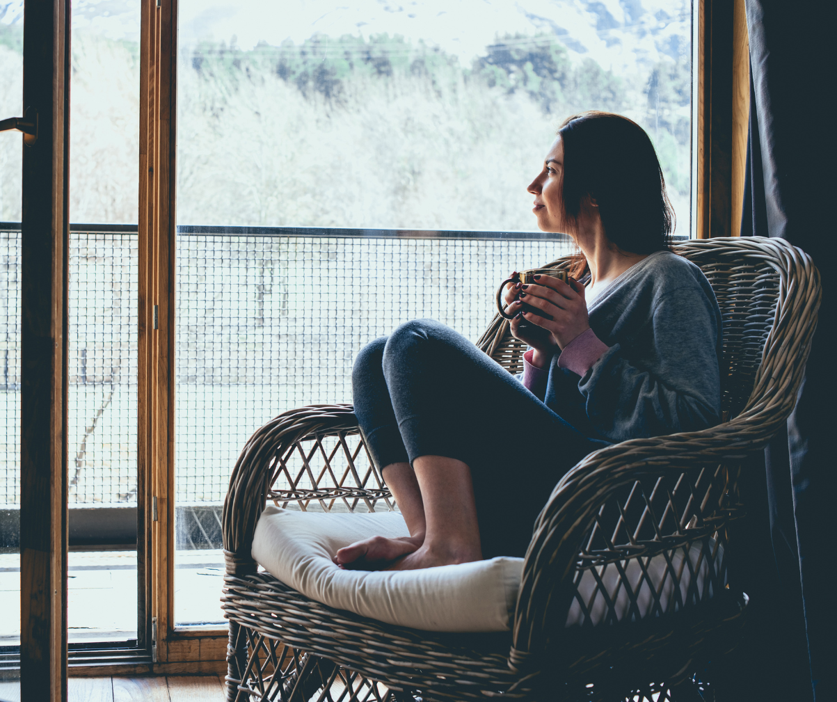 Kuvassa nainen istuu nojatuolissa teekupin kanssa talvella