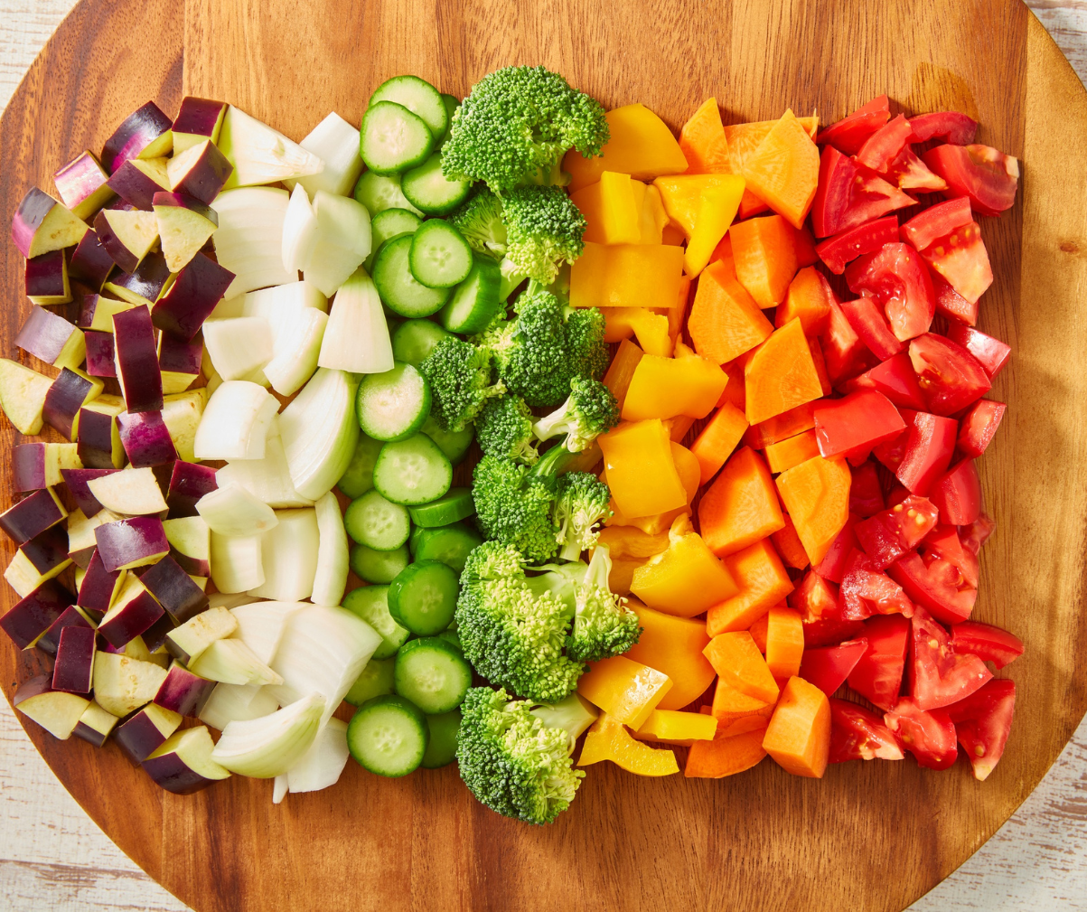 Kuvassa runsaasti vihanneksia ja kasviksia leikattuna leikkuulaudalle