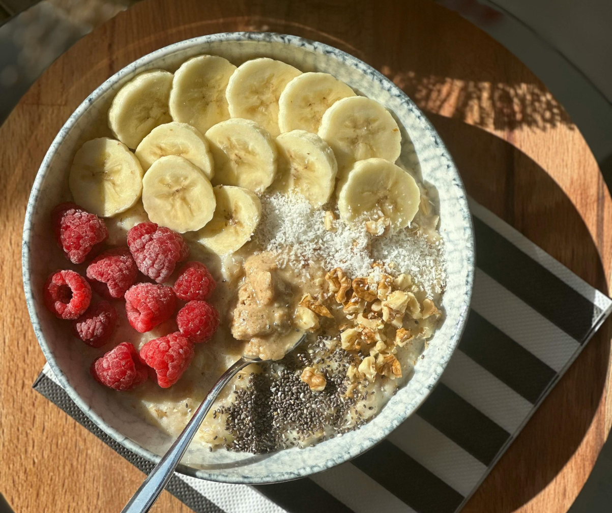 Kuvassa puuroannos, jossa päällä vadelmia, banaania, pähkinöitä ja chia-siemeniä