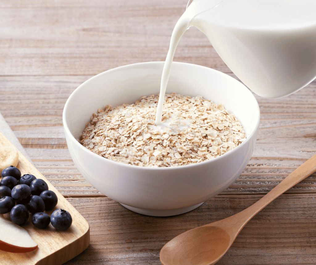 Kuvassa valmistetaan kaurapuuroa; kaurahiutaleet kulhossa ja niiden päälle kaadetaan maitoa