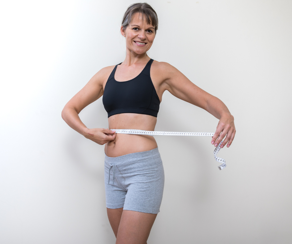 Nainen mittaa vyötärönympärystään mittanauhalla.