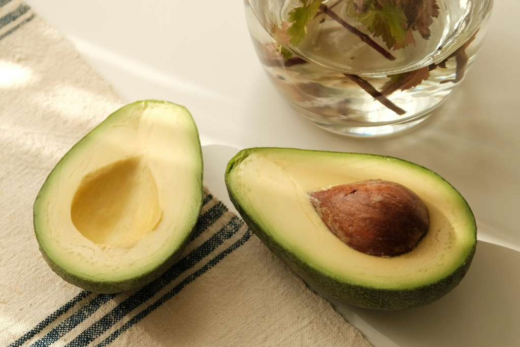 Halkaistu avokado pöydällä: toisessa puolikkaassa kivi, toisessa tyhjä kolo.