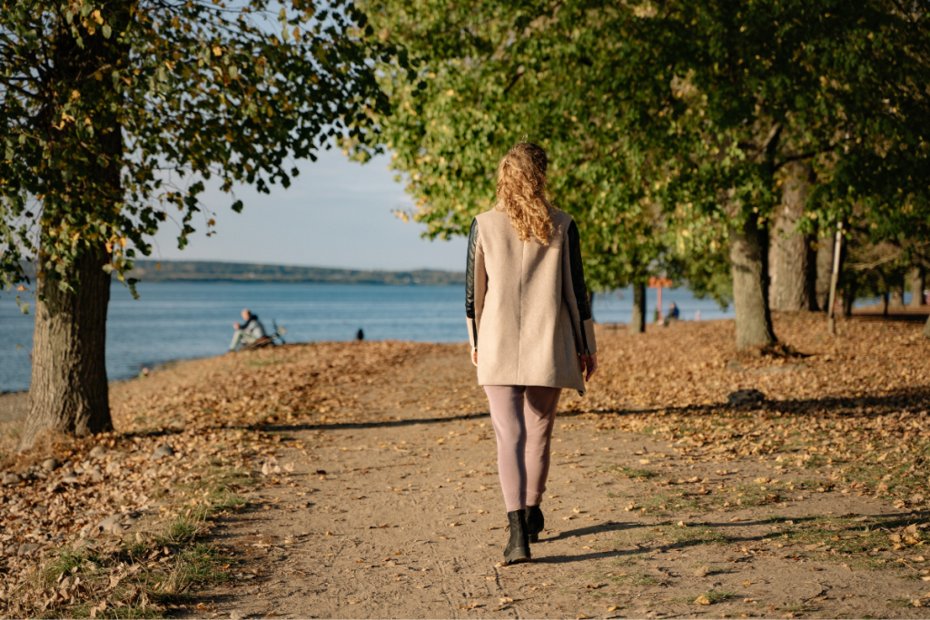 Nainen kävelee meren rannalla syksyllä.