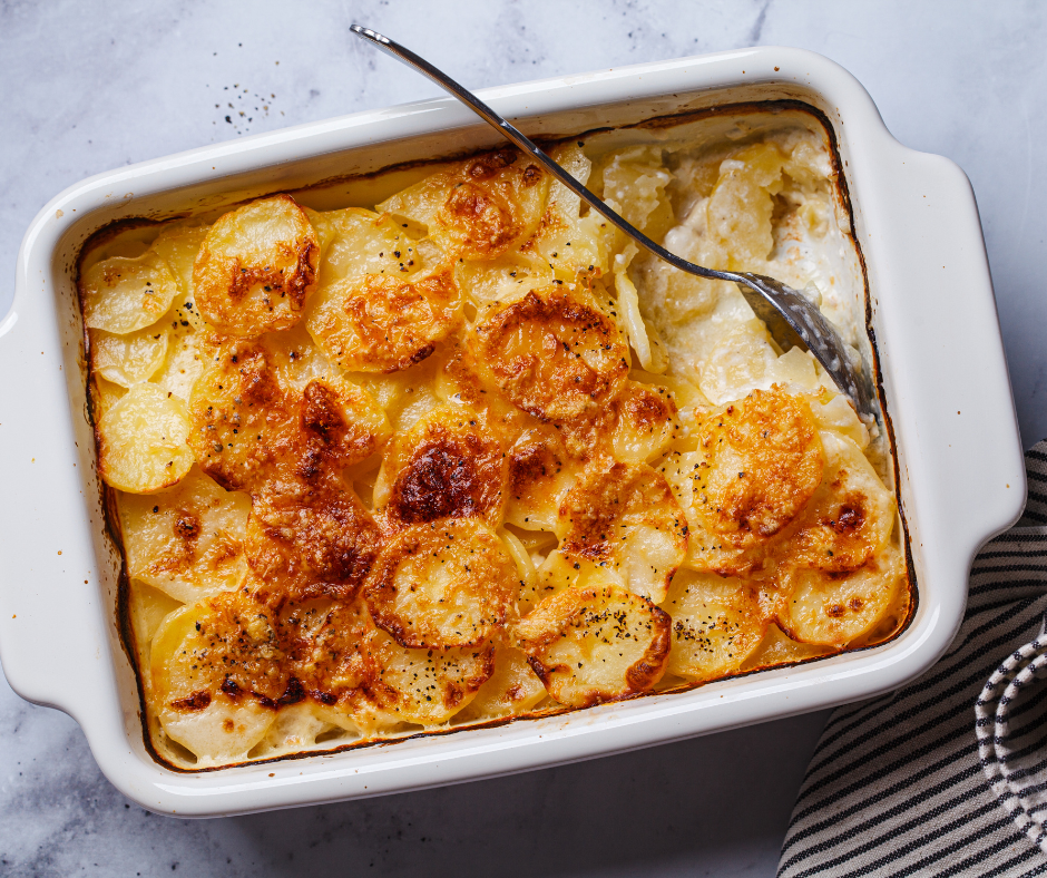 Laatikollinen valkosipuliperunoita. Lusikka pystyssä ruoassa.