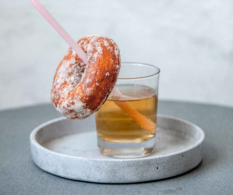 Pöydällä lasi, jonka pilliin on upotettu munkki.