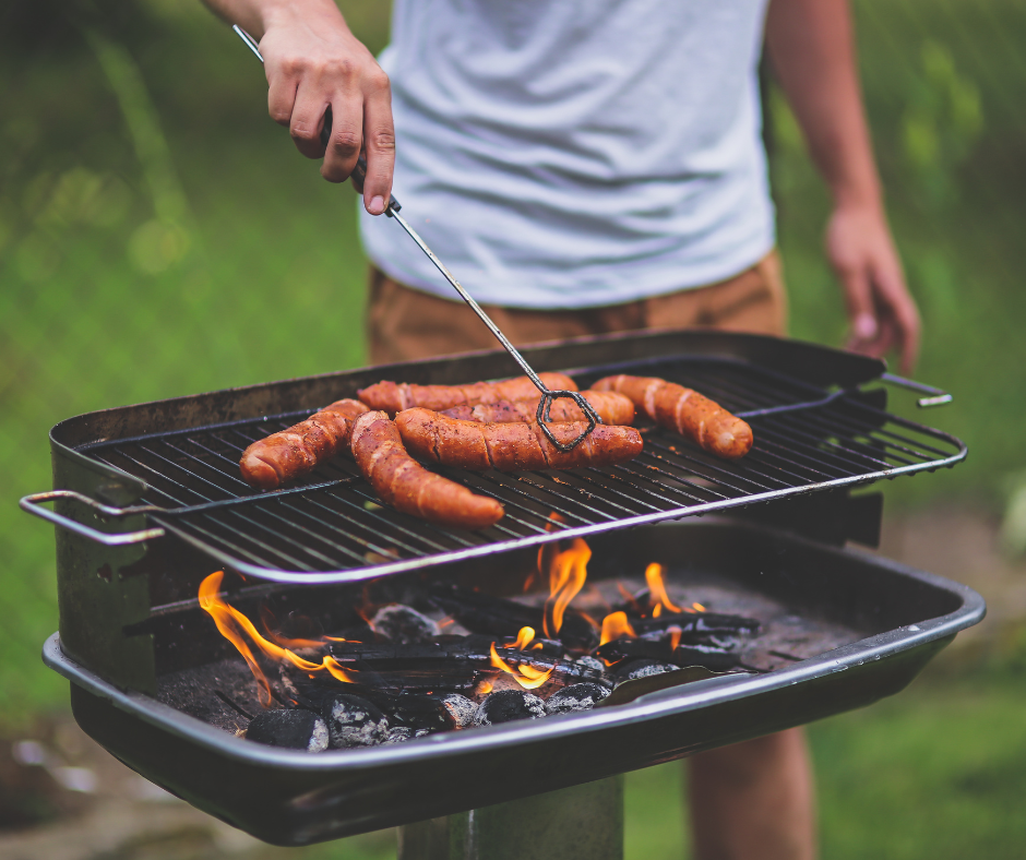 Mies grillaa makkaroita grillissä.