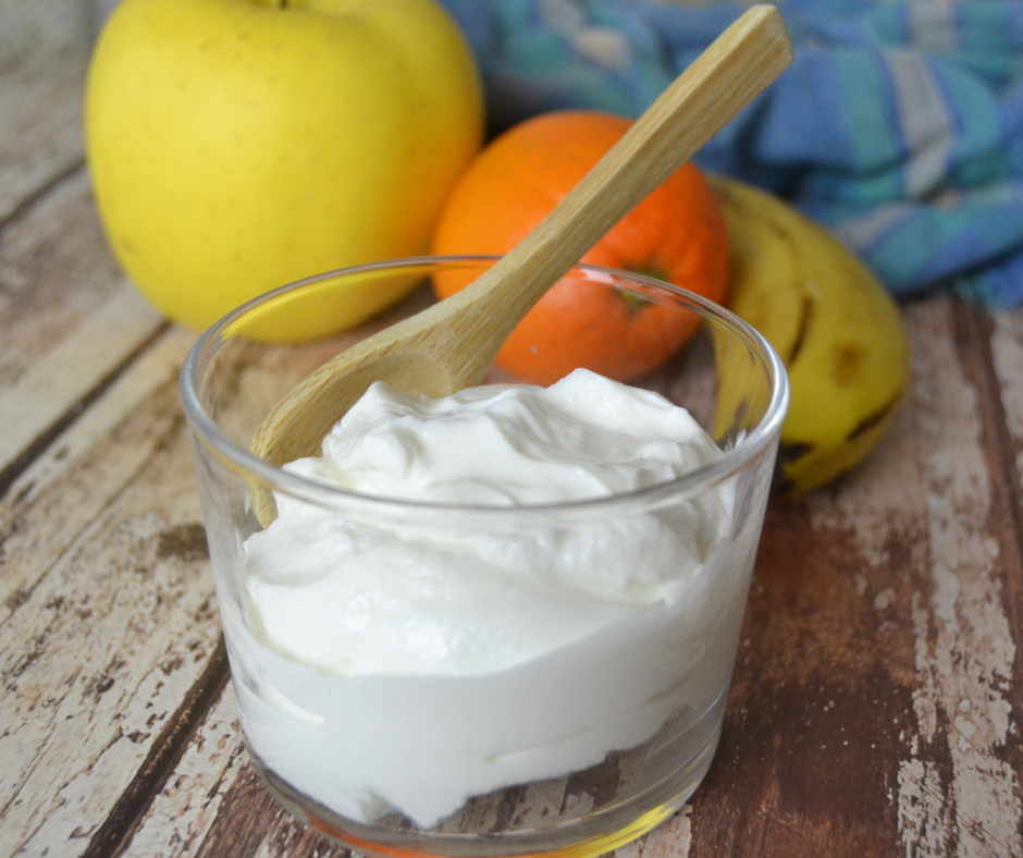 Kipossa skyr-rahkaa, taustalla hedelmiä, banaani, omena ja mandariini.