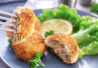 Lähellä lohipihvin pala haarukassa. Taustalla lautanen, jossa pihviä.