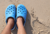 Miehen jaloissa siniset crocs-kengät.