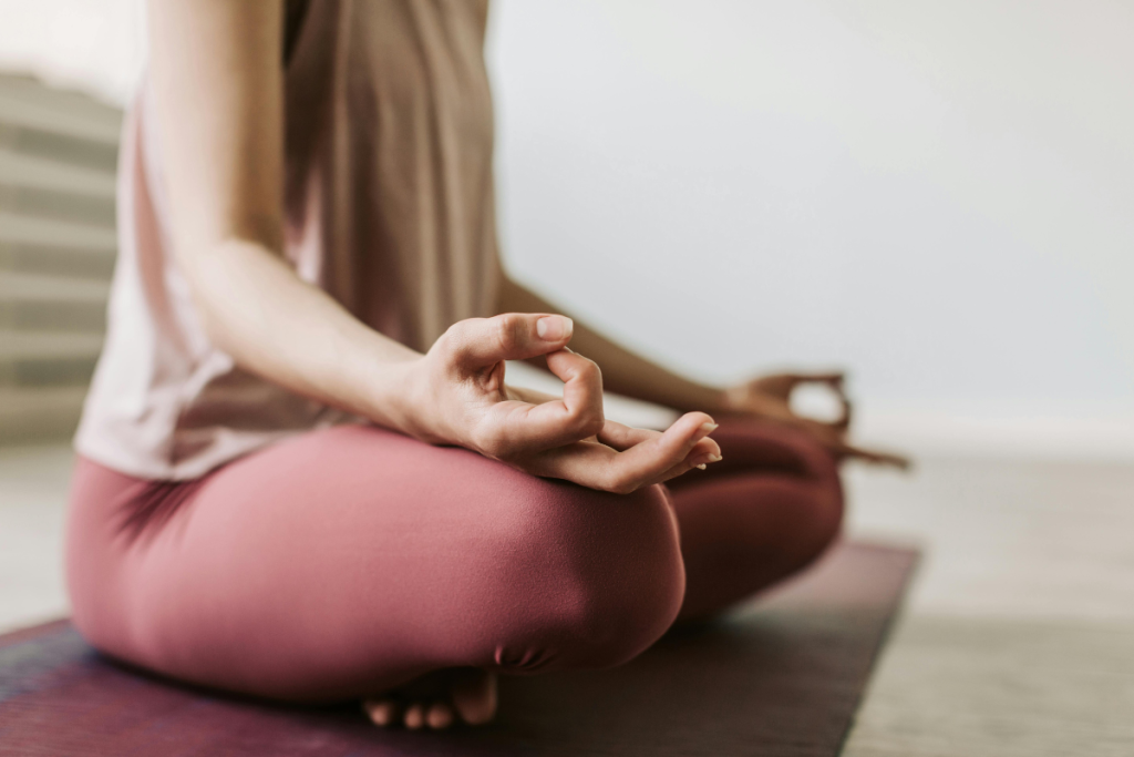 Urheilullinen nainen tekemässä meditaatiota jumppamatolla.
