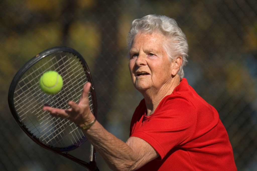Vanhempi nainen pelaa tennistä.