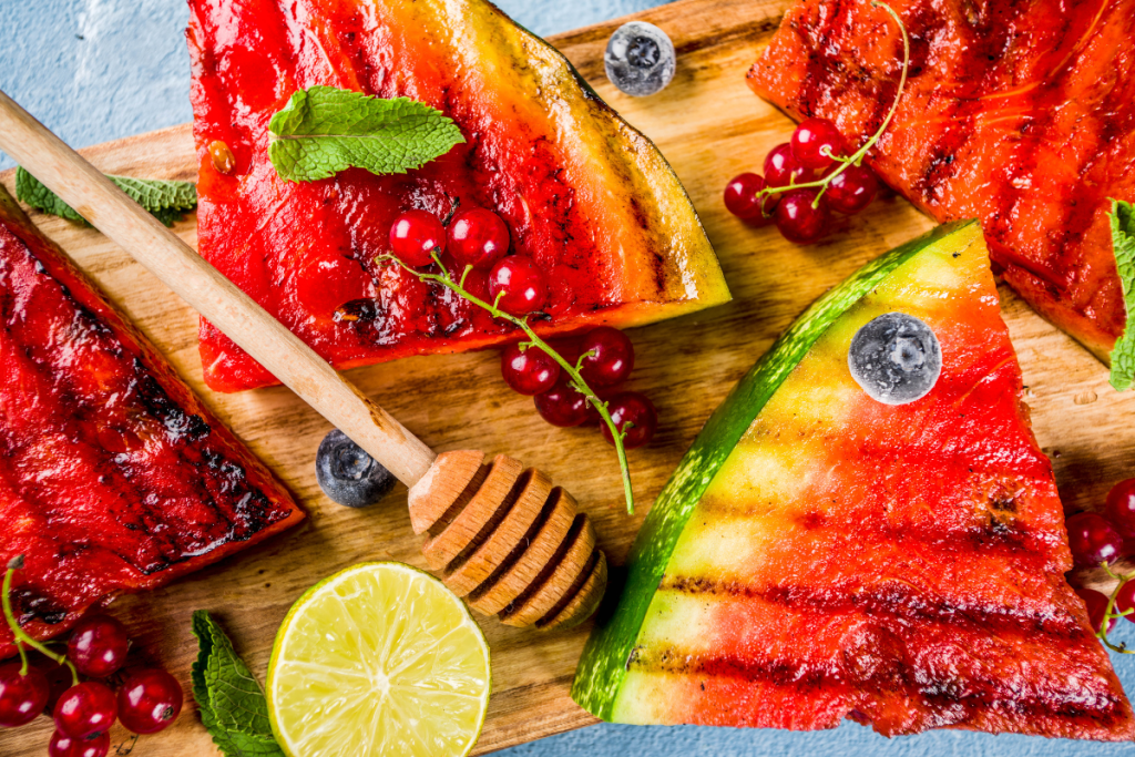 Grillattuja vesimelonin viipaleita, limeä, hunajaa ja marjoja.