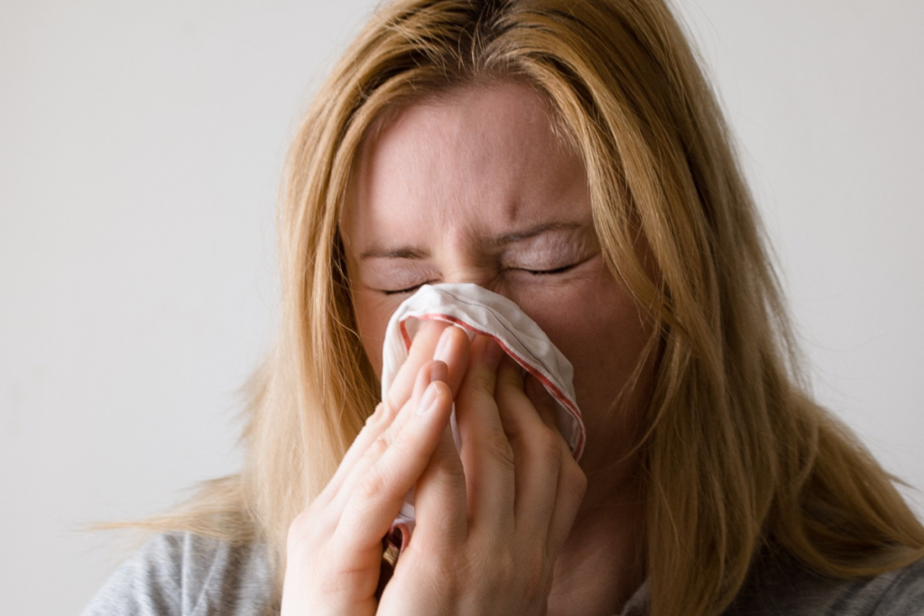 Allergiaoireet. Nainen niistää nenää.