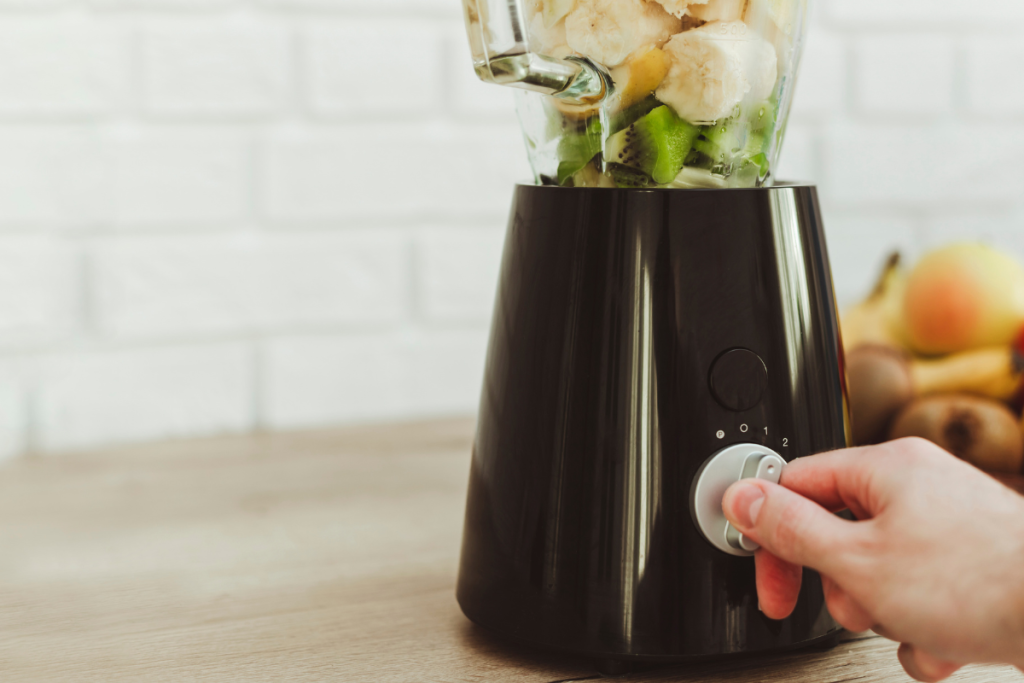 Henkilö painamassa tehosekoittimen nappulaa. Smoothien teko.